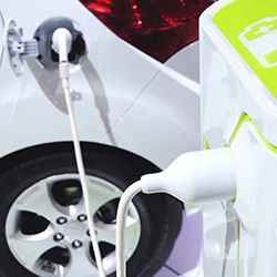 electric car charger plugged into a white car at home